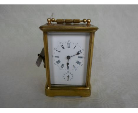 A French gilt brass carriage clock, having five panelled bevel edged glass, the bell striking movement behind an enamel dial 