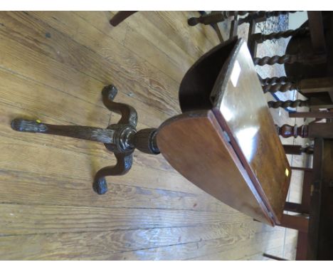 A George III style mahogany tripod table, the rotating oval  top with drop leaves over a ribbon carved stem and acanthus carv