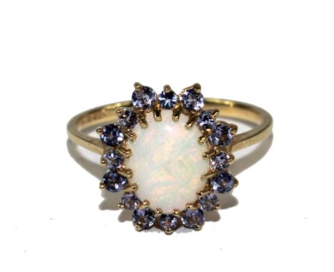 A 9 carat gold ring set with central opal with tanzanite border