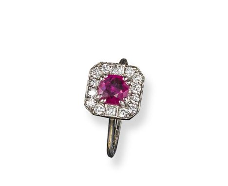 A ruby and diamond cluster ring, the circular-shaped ruby is set within a border of twelve round brilliant-cut diamonds and t