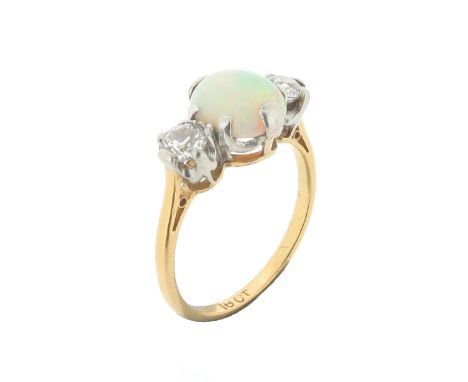 An opal and diamond three stone ring, the solid white opal is set with a circular-cut diamond to each side in platinum and ye