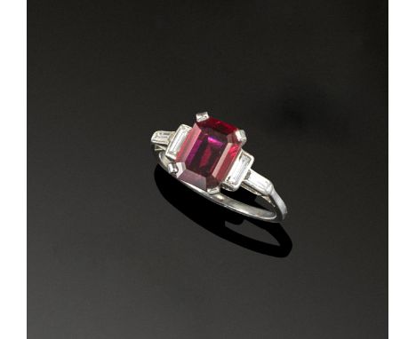 A ruby and diamond ring, the emerald-cut ruby is set with baguette-shaped diamonds to the shoulders. Size M. Accompanied by r