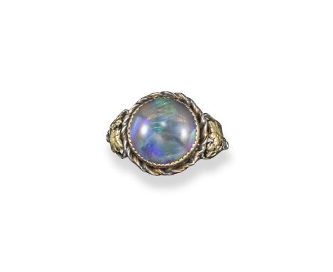 An Art Nouveau opal ring, the solid white opal set within silver and gold scrolling foliate surround. Size P 1/2.