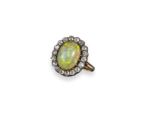 An opal and diamond cluster ring, the solid white opal cabochon is set within a surround of old circular-cut diamonds in silv