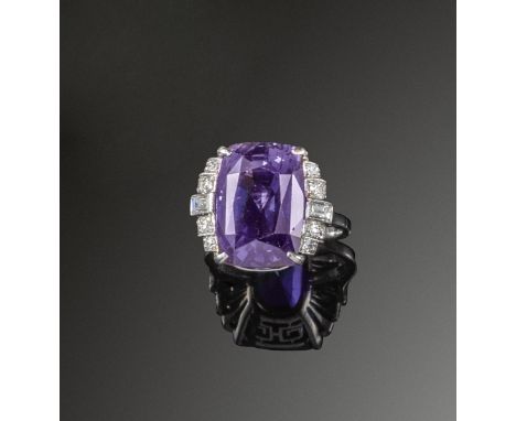 A cushion-shaped colour change sapphire and diamond ring, set with graduated circular and baguette-shaped shoulder diamonds i