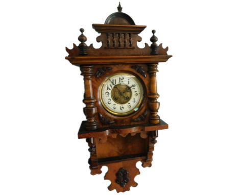 A late 19thC Continental walnut wall clock, with a spindled turned shaped crest, the dial with Arabic numerals flanked by tur