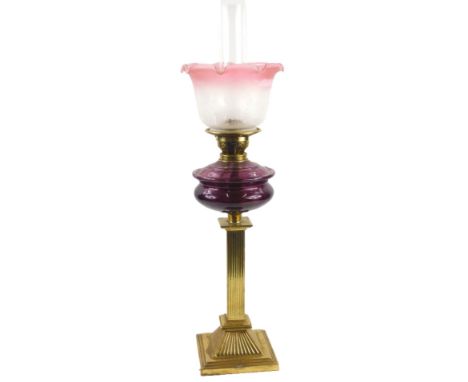 A Victorian style brass column oil lamp, with a ruby tinted reservoir and an Art Nouveau style frosted pink glass shade, 72cm