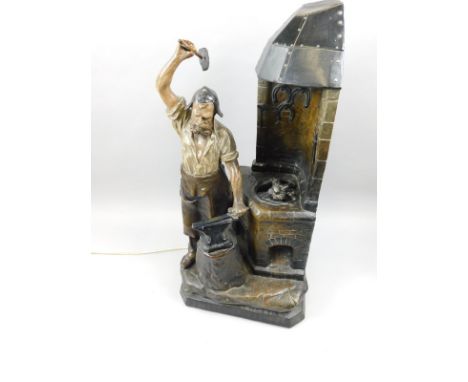 A late 19th/early 20thC French cold painted spelter lamp base, modelled in the form of a blacksmith in his shop, bearing name