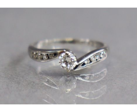 A diamond ring, the centre brilliant-cut stone approx. 0.2carat, smaller diamonds to the scroll shoulders, set to an 18ct whi