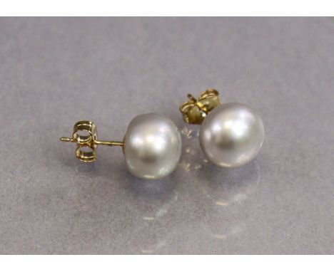 A pair of 9ct gold ear studs, each set large cultured button pearl, each approx. 9mm dia.