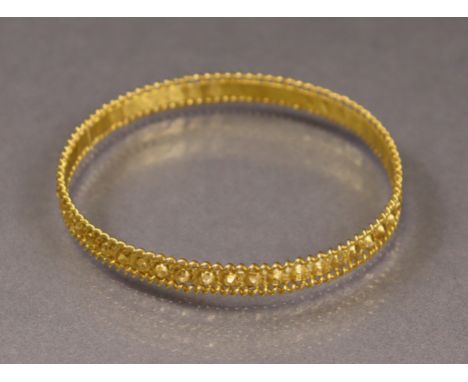 An Egyptian gold stiff bangle with continuous ‘nail-head’ design within coiled wire rims (20.5g).