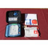 A Philips HeartStart defibrillator in hard carry case, with owners manual, and a smart pad cartridge