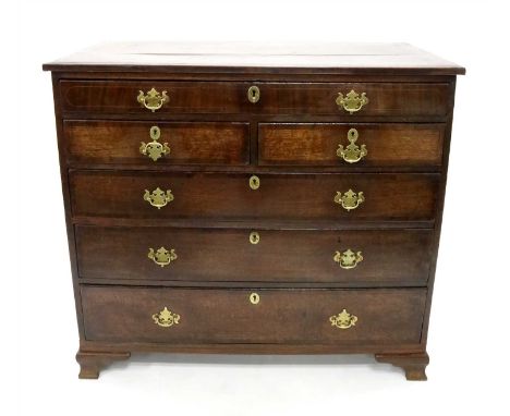 An early 19th century country oak chest of drawers, the caddy top with generous stepped cross-banded borders above an alignme