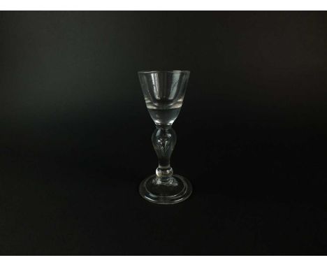 A heavy baluster wine or dram glass circa 1710 the funnel bowl set on solid circular base, inverted baluster stem with a tear