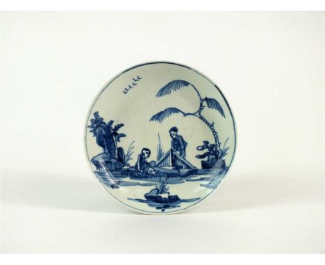 A Vauxhall porcelain blue and white saucer circa 1775-57, painted with two figures, fence, tree, rock and birds, unmarked, 11