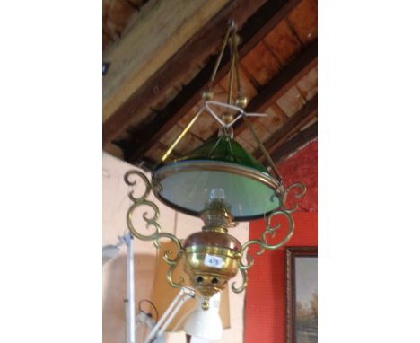 A brass hanging oil lamp with scroll supports and green glass shade