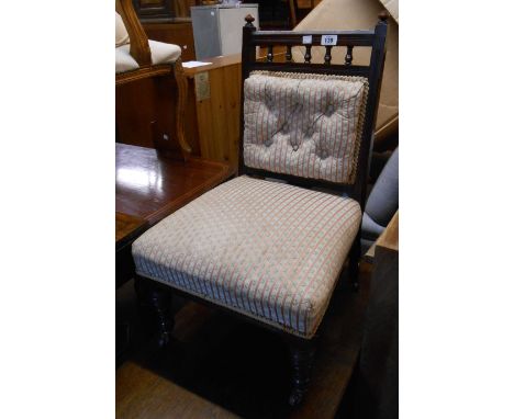 An Edwardian stained walnut framed boudoir nursing chair with button back upholstery, set on turned front legs and casters