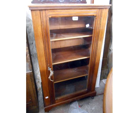 A 55.5cm Edwardian walnut pier cabinet with a low raised back and shelves enclosed by a glazed panel door, set on bracket fee