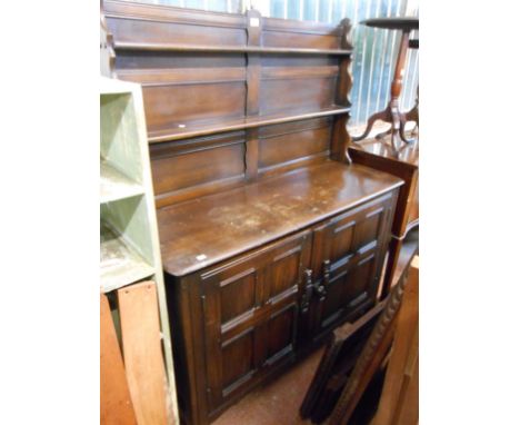 A 1.22m Ercol dark stained elm two part dresser with two shelf open plate rack over a base enclosed by a pair of panelled cup