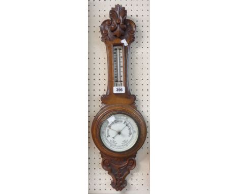 A late Victorian polished carved oak cased banjo barometer/thermometer with ceramic dial and aneroid works