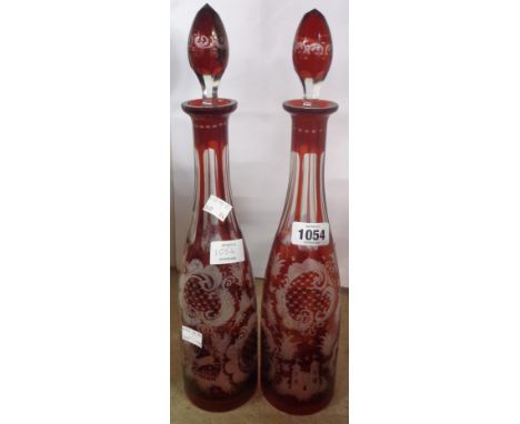 A pair of old Bohemian ruby flash cut glass decanters decorated with castles, stags, birds, and Rococo scrolls