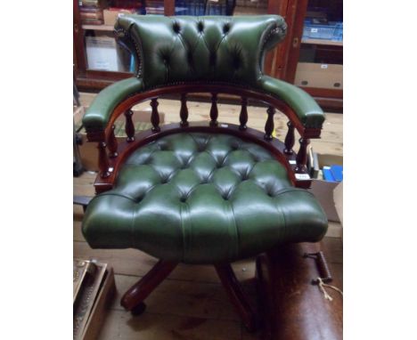A modern reproduction mahogany framed captain's swivel chair upholstered in studded button back green leather, set on five mo