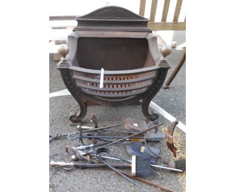 A large cast iron fire grate with brass finials, and various fire tools