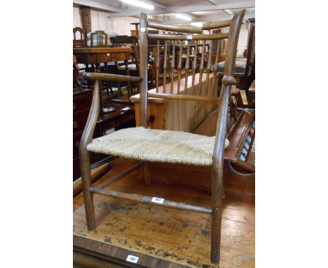 An antique stained wood framed stick back elbow chair with woven seagrass seat and turned front stretcher - top rail cracked