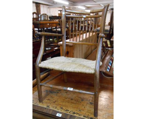 An antique stained wood framed stick back elbow chair with woven seagrass seat and turned front stretcher - top rail cracked