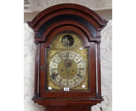 An antique mahogany longcase clock with flanking turned spindles to hood, the 13" arched brass and silvered dial with moving 