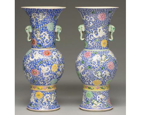 A pair of Chinese blue ground famille verte vases, 20th c, of gu form with elephant head handles, enamelled with mythical bea