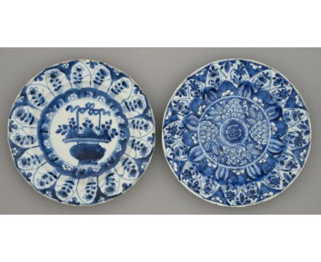 Two Chinese blue and white plates, Kangxi period, painted with a flower filled basket or formal floral design in lappet borde