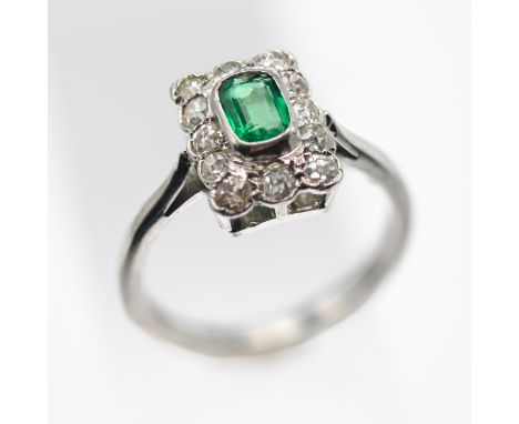 An emerald and diamond cluster ring, size N/O (not hallmarked).