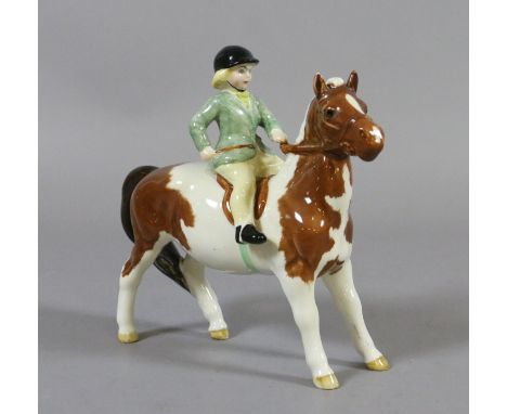 A Beswick model of a girl riding on a skewbald pony.