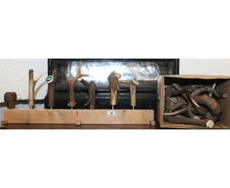 Seven ramblers walking stick handles mounted on a stand along with a box of antlers.