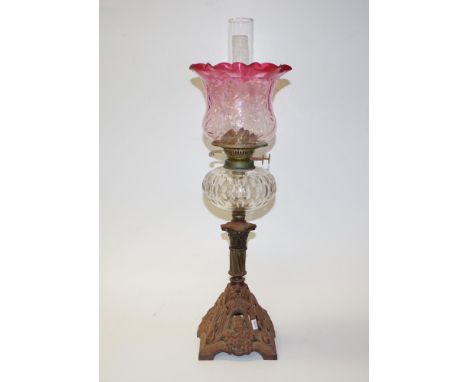 Antique cast iron based ruby glass banquet lamp decorated cast iron base, to decorated column, supporting a clear glass reser