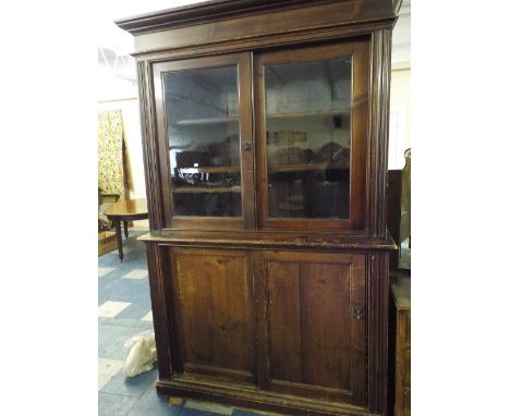 A Stained Pine Housekeepers Cupboard with Glazed Shelf Top Section and Sliding Doors to Base.