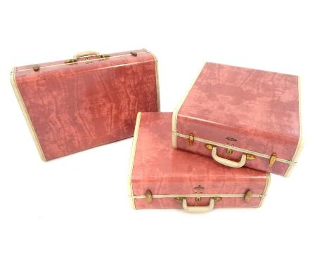 A graduated set of three vintage Samsonite suitcases, pink with ivory coloured trim and brass fittings, largest 46 x 66 x 23c