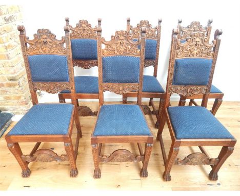 A set of six late C19th Flemish oak dining chairs, ornately carved with a green man mask to the splat, upholstered in blue to