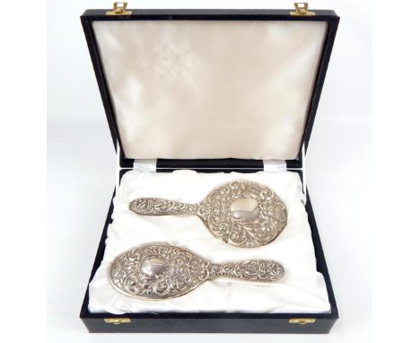 Cased silver back mirror and hairbrush, bird, mask and scroll repousee decoration.