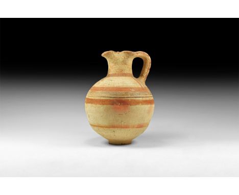 10th-6th century BC. A terracotta globular jug with basal ring, broad tubular neck with pinched sides and pouring lip, strap 