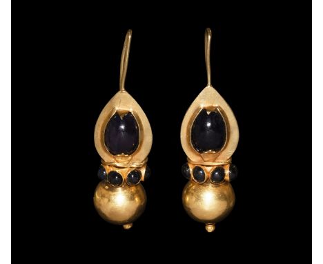 19th century AD. A matched pair of gold earrings, each a hollow-formed teardrop body with hook and inset dark ruby cabochon, 