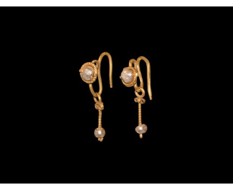 7th-9th century AD. A matched pair of gold earrings each an S-shaped wire loop, beaded wire rim and pearl bead finial, dangle