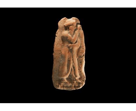 19th-17th century BC. A tongue-shaped ceramic plaque with a low relief figure of a standing bearded male, dressed in a long r