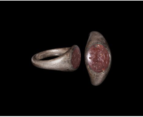1st-2nd century AD. A D-section silver ring with insert red stone intaglio, engraved standing figure holding a bag to the fro