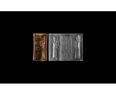 1900-1530 BC. A black jasper cylinder seal with panel of text flanked by two opposed figures, suppliant goddesses standing on