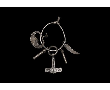 9th-11th century AD. A silver amuletic pendant group on a suspension ring comprising: a crescentic plaque with twisted wire f