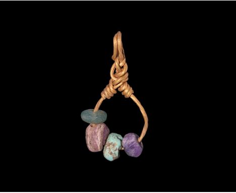 9th-11th century AD. A pendant comprising: gold wire hoop with twisted loops, ends coiled about the shank; plano-convex ameth