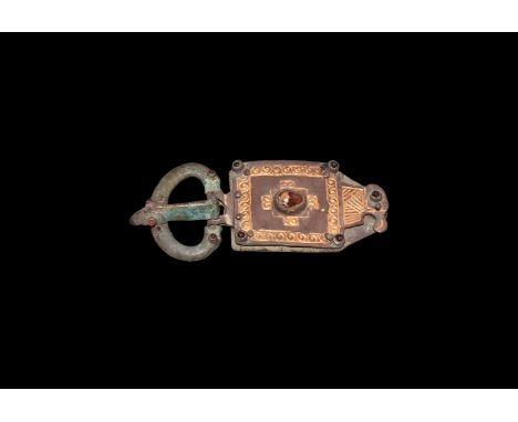 6th century AD. A silver belt buckle comprising: convex loop with animal-head finials, each with a garnet cabochon eye in a r