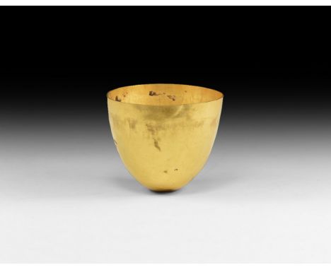 2nd-1st century BC. A gold cup formed from a single sheet of metal, with thin rim and body tapering to the rounded base; smal